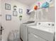 Functional laundry room features a washer, dryer, shelving, and decor at 8685 Sw 49Th Cir, Ocala, FL 34476
