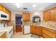 Well-lit kitchen featuring oak cabinetry, tiled backsplash and flooring and modern appliances at 9085 Sw 96Th Ln # B, Ocala, FL 34481