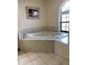 Bathroom features garden tub with tiled surround and an arched window for natural light at 9923 Se 64Th Ave, Belleview, FL 34420