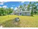 Spacious backyard, showcasing the home's exterior with a fire pit and lush grass at 1133 Nw 122Nd Pl, Citra, FL 32113