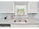 Close-up of kitchen sink with granite countertops, white cabinets, and a window at 1133 Nw 122Nd Pl, Citra, FL 32113