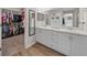 Bright bathroom featuring a double vanity, storage cabinet, wood-look flooring and a large walk-in closet at 11330 Sw 61St Cir, Ocala, FL 34476