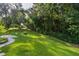 Lush backyard with mature trees, well-manicured lawn, and view of the home in the background at 11598 Sw 74Th Ct, Ocala, FL 34476