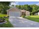 Charming single-story home showcasing a long driveway and a well-manicured lawn, complete with an attached two-car garage at 11598 Sw 74Th Ct, Ocala, FL 34476