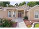 Inviting front entryway with a decorative wreath, tiled walkway, and meticulously manicured landscaping at 11598 Sw 74Th Ct, Ocala, FL 34476