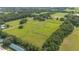Aerial view showcases the property's vast green pastures, mature trees, and fenced perimeter at 1501 Ne 97Th Street Rd, Anthony, FL 32617