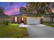 Charming single-story brick home with a well-manicured lawn and a two-car garage at dusk at 2127 Ne 38Th Ter, Ocala, FL 34470