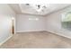 A bright main bedroom featuring neutral walls, plush carpet, and a tray ceiling at 2127 Ne 38Th Ter, Ocala, FL 34470