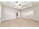 A bright main bedroom featuring neutral walls, plush carpet, and a tray ceiling at 2127 Ne 38Th Ter, Ocala, FL 34470