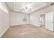A bright main bedroom featuring neutral walls, plush carpet, a tray ceiling, and access to the bath at 2127 Ne 38Th Ter, Ocala, FL 34470