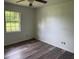 This bedroom features wood-look floors, a ceiling fan, and a window offering natural light at 4701 Ne 9Th St, Ocala, FL 34470