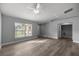 Bright living room features wood-look floors, a ceiling fan, and a window with natural light at 51 Pine Trace Loop, Ocala, FL 34472