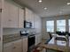 Well-lit kitchen with stainless steel appliances, granite countertops, and white cabinetry for ample storage at 5962 Sw 80Th Ln, Ocala, FL 34476