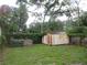 Spacious backyard featuring a shed, green grass, a wooden fence and large trees at 6141 Nw 64Th Ct, Ocala, FL 34482