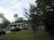 Landscaped front yard view of property showing a stone-accented home and mature trees at 6141 Nw 64Th Ct, Ocala, FL 34482
