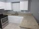 Updated kitchen featuring white cabinetry, granite countertops, and stainless steel appliances at 6141 Nw 64Th Ct, Ocala, FL 34482