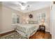 Bright bedroom featuring hardwood floors, plantation shutters, and a charming queen bed with patterned bedding at 7563 Nw 21St St, Ocala, FL 34482