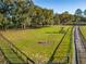Aerial view of a green fenced pasture featuring a bench under a tree at 7563 Nw 21St St, Ocala, FL 34482