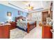 Main bedroom with blue accent wall, tray ceiling, ceiling fan, tiled floor, and plantation shutters at 7814 Sw 97Th Cir, Ocala, FL 34481