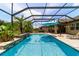 Sparkling screened pool with waterfall and lush tropical plants offers a tranquil retreat at 7814 Sw 97Th Cir, Ocala, FL 34481