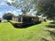 Backyard featuring a manicured lawn, mature trees, screened-in lanai, and lush landscaping at 8303 Sw 78Th Cir, Ocala, FL 34476