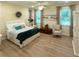 Comfortable bedroom features a decorative wreath, wood floors, a sitting chair, and two bright windows at 8303 Sw 78Th Cir, Ocala, FL 34476
