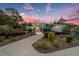 A beautifully landscaped home featuring an inviting walkway with a striking sunset backdrop at 8605 Sw 209Th Court Rd, Dunnellon, FL 34431