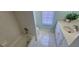 Bathroom featuring marble tiling, a tub and shower combo, vanity and a bright window at 8771 Sw 115Th St, Ocala, FL 34481