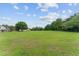 Expansive grassy property surrounded by mature trees and a blue sky with fluffy clouds at 9095 Sw 9Th Ter, Ocala, FL 34476