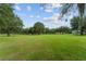 Expansive grassy property with mature trees, blue sky, and partial view of the house at 9095 Sw 9Th Ter, Ocala, FL 34476