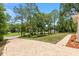 Long, brick driveway leads to a sprawling backyard with views of the surrounding lush greenery and mature trees at 9180 Sw 202Nd Avenue Rd, Dunnellon, FL 34431