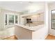 Kitchen with breakfast bar, white appliances, tile flooring, and a view of the bright dining area at 9180 Sw 202Nd Avenue Rd, Dunnellon, FL 34431