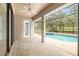 Covered patio leading to a screened pool area with a jacuzzi and lush backyard views at 9180 Sw 202Nd Avenue Rd, Dunnellon, FL 34431