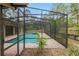 Screened-in pool with brick pavers and adjacent hot tub with view of the yard at 9180 Sw 202Nd Avenue Rd, Dunnellon, FL 34431