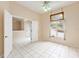 Bedroom with white tile flooring, a ceiling fan, and a view of the backyard through a decorated window at 9213 Sw 197Th Cir, Dunnellon, FL 34432
