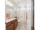 Bathroom with granite vanity, white tiled shower and tub, and neutral tiled floors at 9236 Sw 91St Court Rd, Ocala, FL 34481