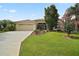 Charming single-story home boasts a well-manicured lawn, mature trees, and a two-car garage with a paved driveway at 611 Allenwood Loop, The Villages, FL 32162