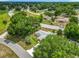 A high aerial view of a single-story home with a well-manicured lawn, mature trees, and access to a main road at 10459 Sw 62Nd Ct, Ocala, FL 34476