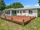 A large wooden deck sits in the backyard of this single story home with white walls and orange accents at 10459 Sw 62Nd Ct, Ocala, FL 34476