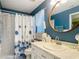 Bathroom with blue walls, patterned floor, shower, and updated vanity with round mirror at 10459 Sw 62Nd Ct, Ocala, FL 34476