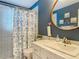 Well-lit bathroom with blue walls and a shower/tub with floral curtain at 10459 Sw 62Nd Ct, Ocala, FL 34476