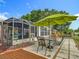 A dining table sits on a tiled patio with a large umbrella and a screened-in porch adjacent to the patio at 10459 Sw 62Nd Ct, Ocala, FL 34476