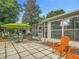 A tiled patio includes a dining table set and orange chairs under an umbrella outside the screen porch at 10459 Sw 62Nd Ct, Ocala, FL 34476