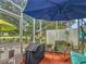 Relaxing screened porch with comfortable seating and a blue patio umbrella at 10459 Sw 62Nd Ct, Ocala, FL 34476