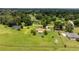 Expansive aerial shot showcasing a lush green lawn, mature trees and landscaping surrounding a single-story home with a brown roof at 12131 Ne 10Th Ter, Ocala, FL 34479