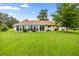 Wide view of the backyard featuring a lawn, enclosed porch, mature trees, and landscaping at 12131 Ne 10Th Ter, Ocala, FL 34479