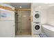 Bathroom showcasing a walk-in shower with glass doors, soaking tub and stacked washer and dryer at 12131 Ne 10Th Ter, Ocala, FL 34479