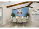 Bright dining room with modern chandelier, wood beams and stylish white table set for eight at 12131 Ne 10Th Ter, Ocala, FL 34479