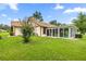 Charming home featuring a sunroom with sliding glass doors, a well-maintained lawn, and mature landscaping at 12131 Ne 10Th Ter, Ocala, FL 34479