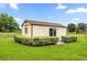Exterior view of the outbuilding featuring a brown roof, and sliding glass doors, surrounded by manicured bushes at 12131 Ne 10Th Ter, Ocala, FL 34479